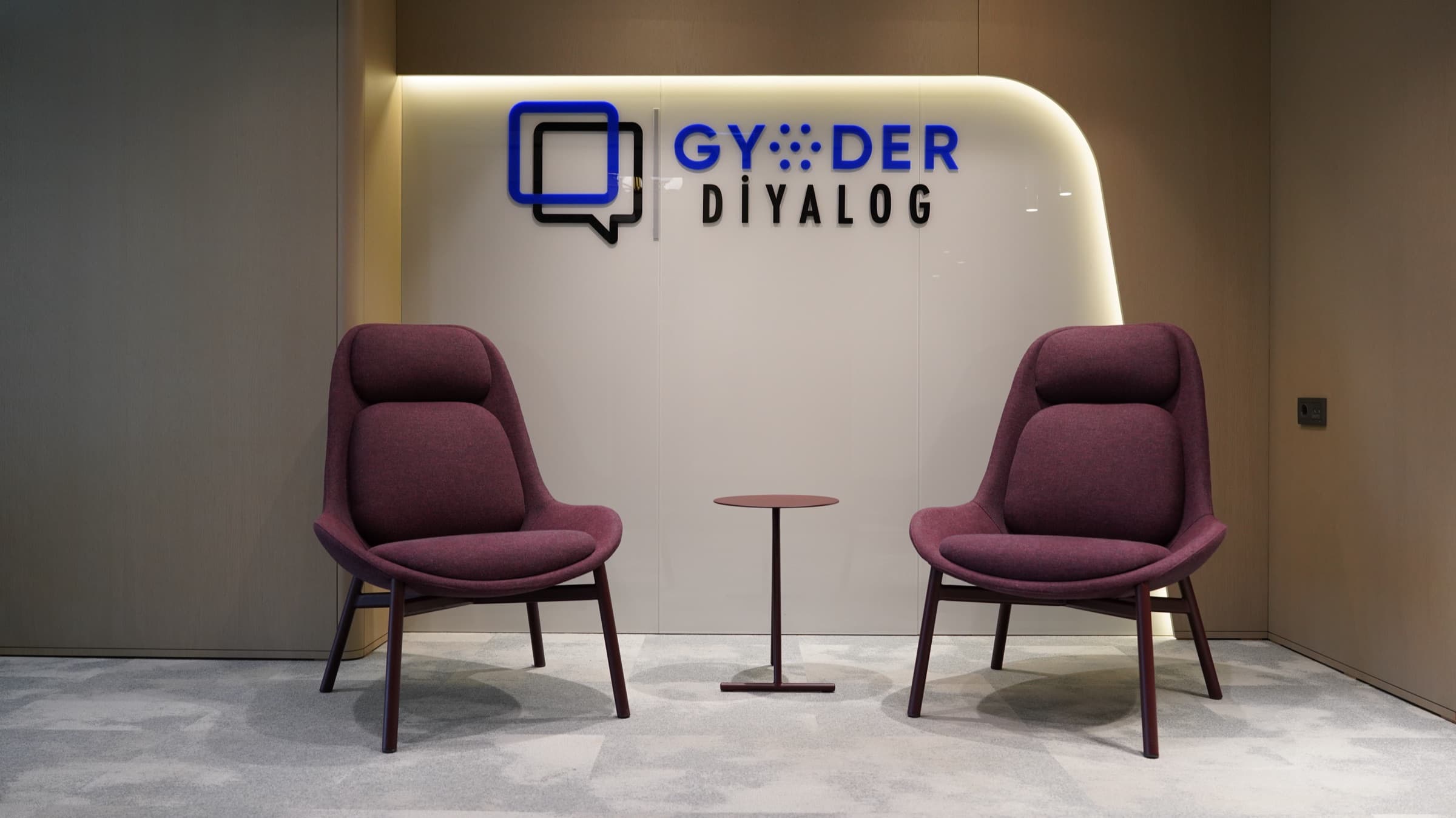 GYODER Diyalog karşılama alanı — logo duvarı önünde iki koltuk